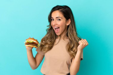 Arkaplanda burger tutan genç bir kadın galibiyeti kutluyor.