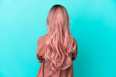 Mavi arka planda pembe saçlı melez bir kadın var.