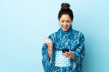 Woman wearing kimono over isolated background surprised and sending a message
