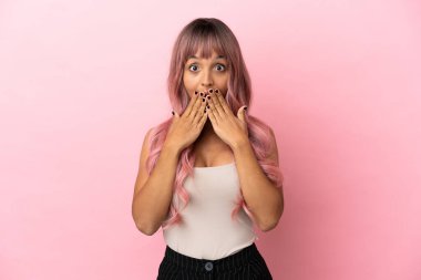 Pembe saçlı melez bir kadın. Pembe arka planda izole edilmiş. Ağzı ve elleri kapalı.