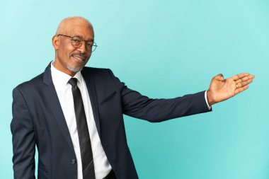 İşletme son sınıf öğrencisi mavi arka planda izole edilmiş ve davet edilmek için ellerini yana uzatıyor.