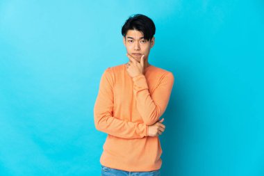 Mavi arka planda mahsur kalmış genç Çinli adamın şüpheleri var.