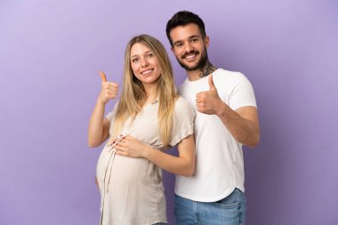 Genç çift hamile ve başparmakları havada.