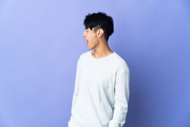 Mor arka planda yalnız yaşayan genç bir Çinli yan yana gülüyor.