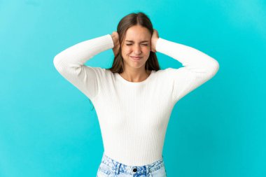 İzole edilmiş mavi arka planı olan genç bir kadın hayal kırıklığına uğramış ve kulaklarını kapatmış.