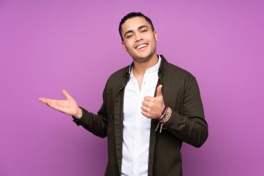 Asyalı yakışıklı bir adam mavi arka planda izole edilmiş. Kopyalama alanı hayali bir şekilde avucunun içinde duruyor. Bir ilan vermek için.