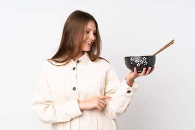 Beyaz arka planda, elinde çubuklarla elinde bir kase şehriye tutarken mutlu bir ifadeyle izole edilmiş beyaz bir kız.