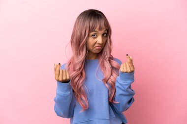 Pembe saçlı melez bir kadın pembe arka planda izole edilmiş para hareketi yapıyor.