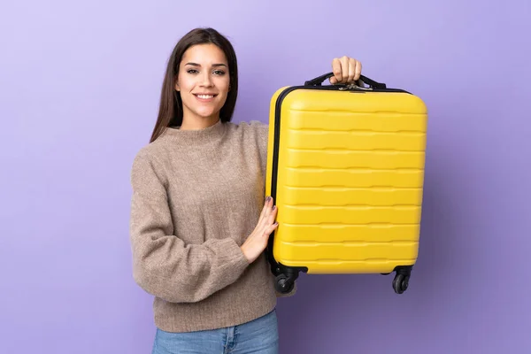 若いです白人女性隔離上の紫の背景で休暇で旅行スーツケース — ストック写真