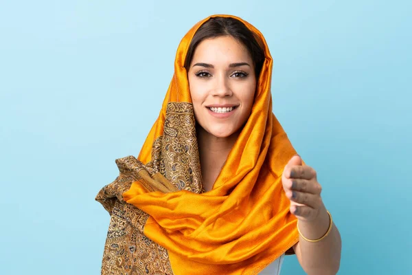 若いですモロッコの女性で伝統的な衣装で隔離された青の背景握手手のために良い取引を閉じる — ストック写真