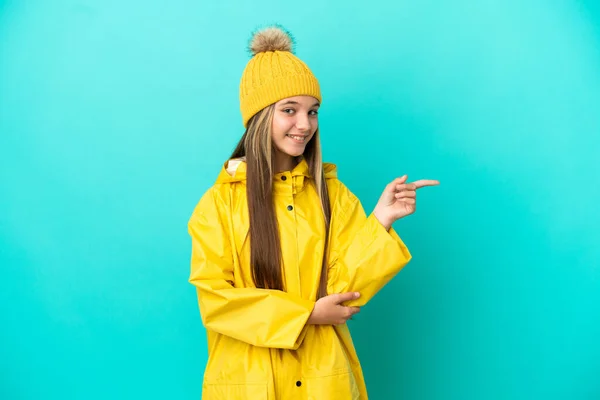 Petite Fille Portant Manteau Imperméable Sur Fond Bleu Isolé Pointant — Photo