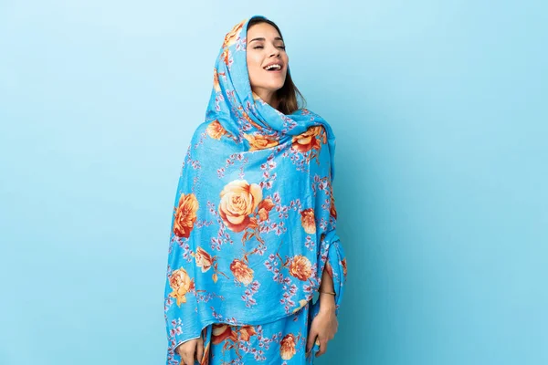 Young Moroccan woman with traditional costume isolated on blue background laughing