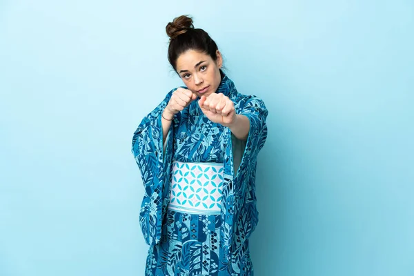 Woman wearing kimono over isolated background with fighting gesture