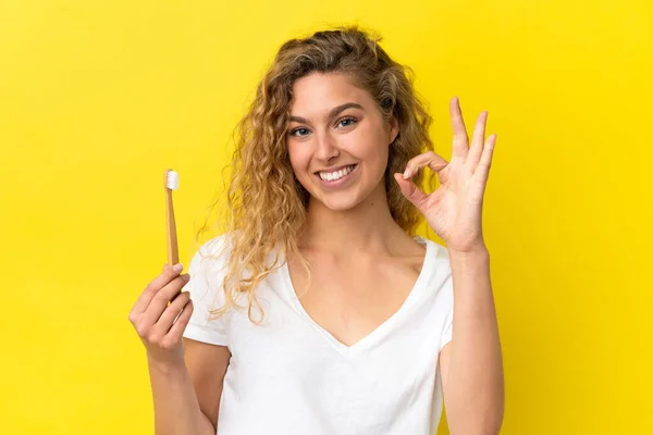 Νεαρή Καυκάσια Γυναίκα Κρατώντας Ένα Βούρτσισμα Των Δοντιών Απομονώνονται Κίτρινο — Φωτογραφία Αρχείου