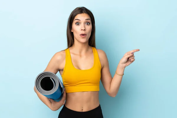 Mujer Deportiva Joven Con Estera Aislada Sobre Fondo Azul Sorprendido — Foto de Stock