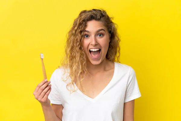 Młoda Biała Kobieta Trzymająca Szczotkujące Zęby Żółtym Tle Zaskakującym Wyrazem — Zdjęcie stockowe