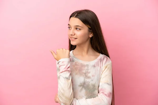 Маленька Дівчинка Над Ізольованим Рожевим Тлом Вказує Бік Щоб Представити — стокове фото