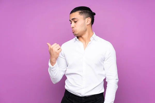 Ásia Bonito Homem Isolado Azul Fundo Infeliz Apontando Para Lado — Fotografia de Stock