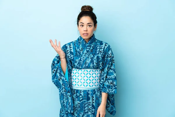 Frau Trägt Kimono Über Isoliertem Hintergrund Und Macht Zweifelnde Geste — Stockfoto