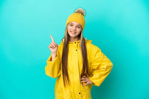 Κοριτσάκι Που Φοράει Αδιάβροχο Παλτό Πάνω Από Απομονωμένο Μπλε Φόντο — Φωτογραφία Αρχείου
