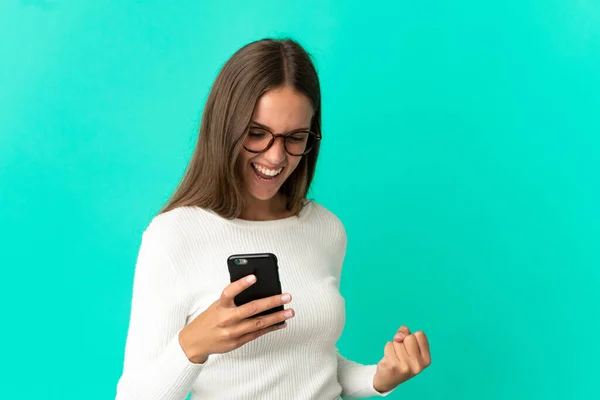 Jonge Vrouw Geïsoleerde Blauwe Achtergrond Met Behulp Van Mobiele Telefoon — Stockfoto