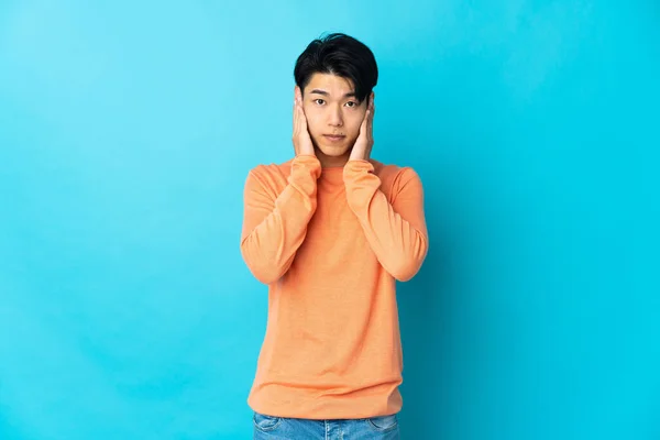Mladý Číňan Izolovaný Modrém Pozadí Frustrovaný Zakrývá Uši — Stock fotografie