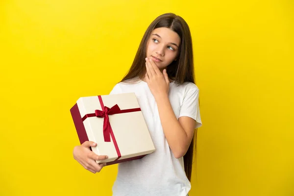 Niña Sosteniendo Regalo Sobre Fondo Amarillo Aislado Mirando Hacia Arriba —  Fotos de Stock