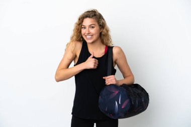 Spor çantalı genç bayan beyaz arka planda izole edilmiş bir şekilde baş parmak hareketi yapıyor.