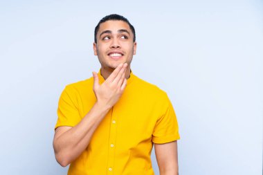 Asyalı yakışıklı adam soyutlanmış arka planda gülümserken yukarı bakıyor