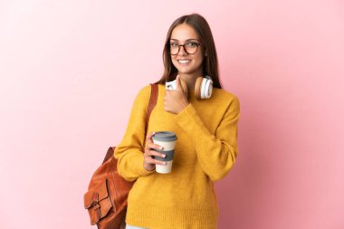 Tecrit edilmiş pembe arka planda genç bir bayan baş parmak hareketi yapıyor.