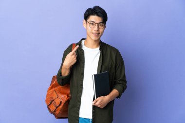 Mor arka planda izole edilmiş genç bir bayan baş parmak hareketi yapıyor.