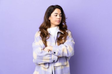 Woman over isolated purple background keeping the arms crossed