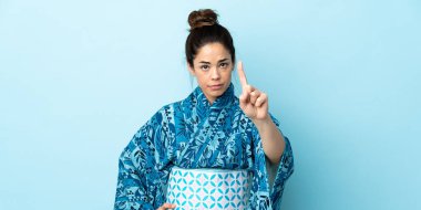 Woman wearing kimono over isolated background counting one with serious expression