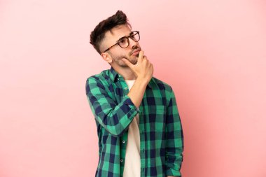 Pembe arka planda izole edilmiş genç beyaz adamın şüpheleri var.