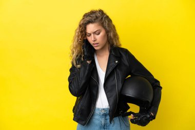 Sarı arka planda başağrısı olan motosiklet kasklı genç sarışın kadın.