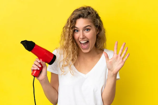 Mujer Rubia Joven Sosteniendo Secador Pelo Aislado Sobre Fondo Amarillo — Foto de Stock