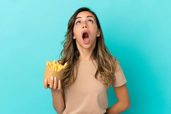 Fiatal Kezében Sült Chips Felett Elszigetelt Háttér Felnéz Meglepett Arckifejezéssel — Stock Fotó