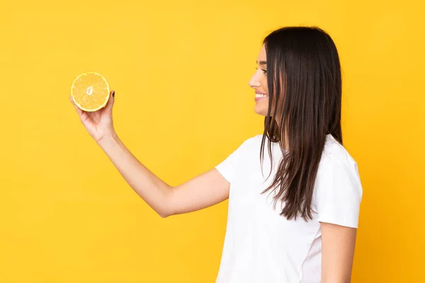 Ung Kaukasiska Kvinna Som Håller Orange Isolerad Gul Bakgrund Med — Stockfoto