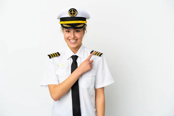 飞机上的金发女飞行员被隔离在白色背景下 指着侧面展示自己的产品 — 图库照片