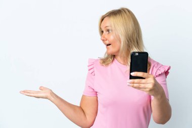 Middle age using mobile phone isolated on white background with surprise facial expression