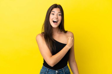 Sarı arka planda izole edilmiş genç Brezilyalı kadın zaferi kutluyor.