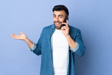 İzole edilmiş mavi arka planı olan beyaz bir adam cep telefonuyla sohbet ediyor.