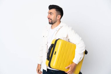 İzole edilmiş beyaz geçmişi olan beyaz bir adam seyahat valiziyle tatilde.