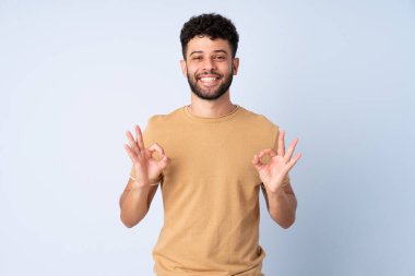 Young Moroccan man isolated on blue background showing ok sign with two hands