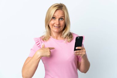 Middle age using mobile phone isolated on white background with surprise facial expression