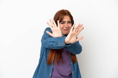 Genç kızıl saçlı kadın, beyaz arka planda izole edilmiş, gergin, ellerini öne uzatıyor.