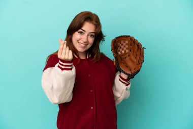 Beyzbol oynayan genç kızıl saçlı kadın mavi arka planda izole bir şekilde para hareketi yapıyor.