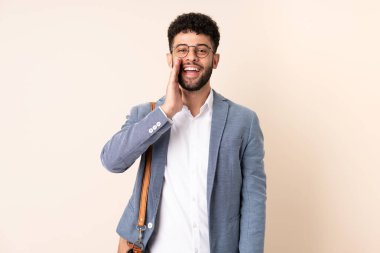 Young business Moroccan man isolated on beige background shouting with mouth wide open