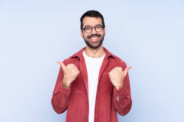 Young caucasian man wearing corduroy jacket over blue background with thumbs up gesture and smiling