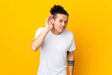 İzole edilmiş arka planda beyaz bir adam bir şey dinlerken elini kulağına koyar.